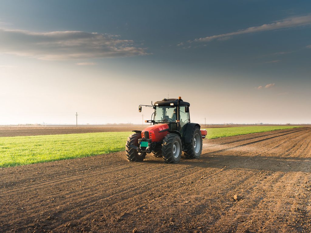 Tractor spreading artificial fertilizers in field